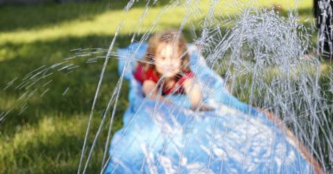 A child playing on a water slide in the garden
